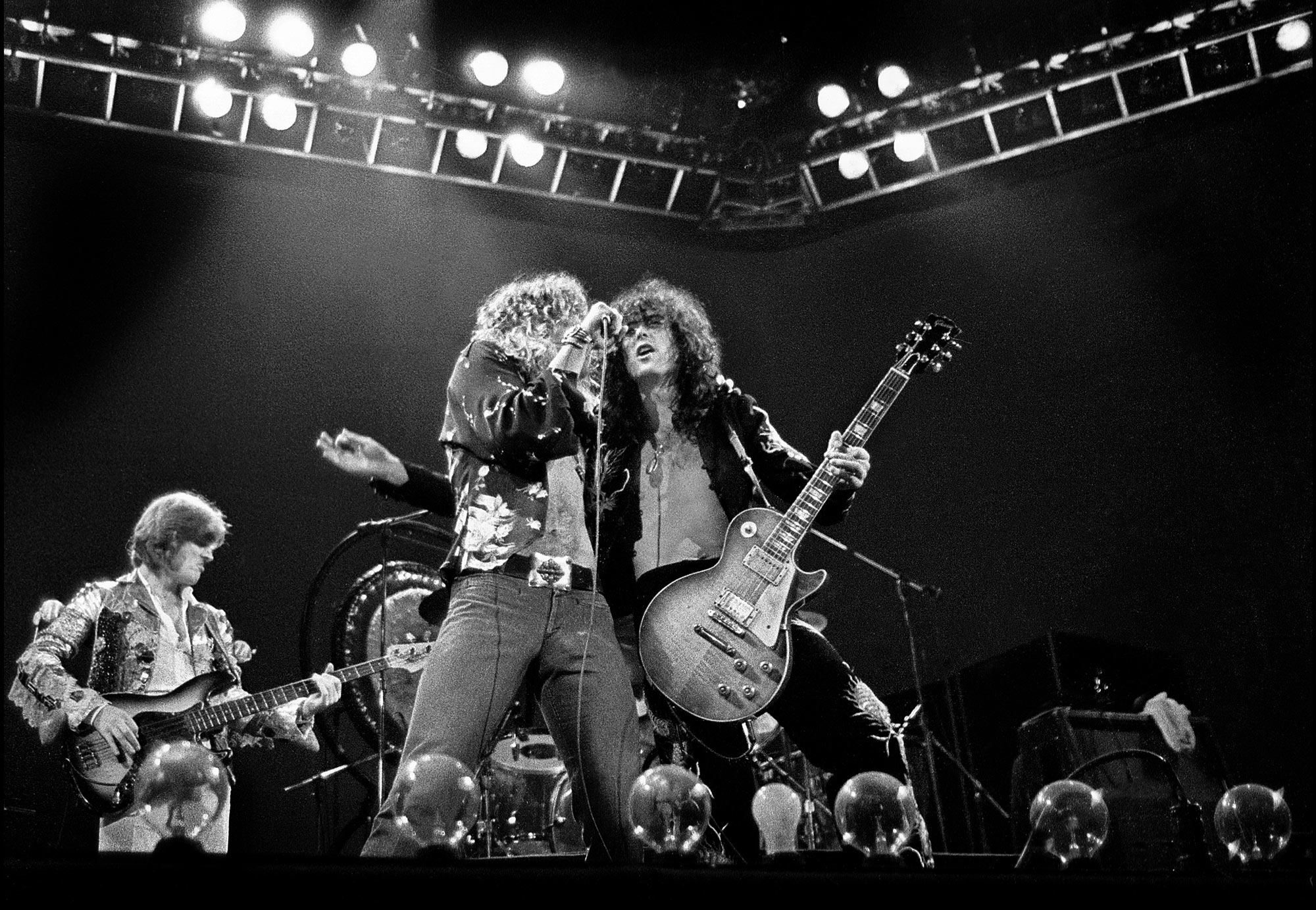 123 ROCK | Led Zeppelin | Robert Plant (Robert Anthony Plant) - August 20, 1948 - West Bromwich, Staffordshire, England, United Kingdom - Lead Vocals, Backing Vocals, Acoustic Guitar, Bass Guitar, Tambourine, Harmonica (1968 - 1980) (1994) (1998), Jimmy Page (James Patrick Page) - January 9, 1944 - Heston, Middlesex, London, England, United Kingdom - Electric Guitars, Rhythm Guitar, Acoustic Guitar, Twelve-string Guitar, Pedal Steel Guitars, Lap Steel Guitar, Slide Guitar, Double Neck Guitar with Six-String and Twelve-String, Bass Guitar, Mandolin, Theremin, Banjo, Dulcimer, The Gizmo, Backing Vocals (1968 - 1980) (1994) (1998), John Paul Jones (John Baldwin) - January 3, 1946 - Sidcup, Kent, London, England, United Kingdom - Bass Guitar, Guitar, Mandolin, Double Bass, Keyboards, Organ, Piano, Acoustic Piano, Electric Piano, Mellotron, Synthesizer, VCS3 Synthesizer, Hohner Clavinet, Hammond Organ, Harpsichord, Moog Synthesizer, Bass Guitar Effects Unit, Recorder, Backing Vocals (1968 - 1980), John Bonham (John Henry Bonham) (Also called : Bonzo, The Beast, Powerhouse) - May 31, 1948 - Redditch, Worcestershire, England, United Kingdom - Drums, Percussions, Timpani, Backing Vocals (1968 - 1980) | Live - Concert - Madison Square Garden - New York City - New York - United States of America - 1977 | Genre : Hard Rock, Heavy Metal, Blues Rock, Folk Rock, Progressive Rock, Psychedelic Rock | Live | Concert | Photo | 23 | Photograph