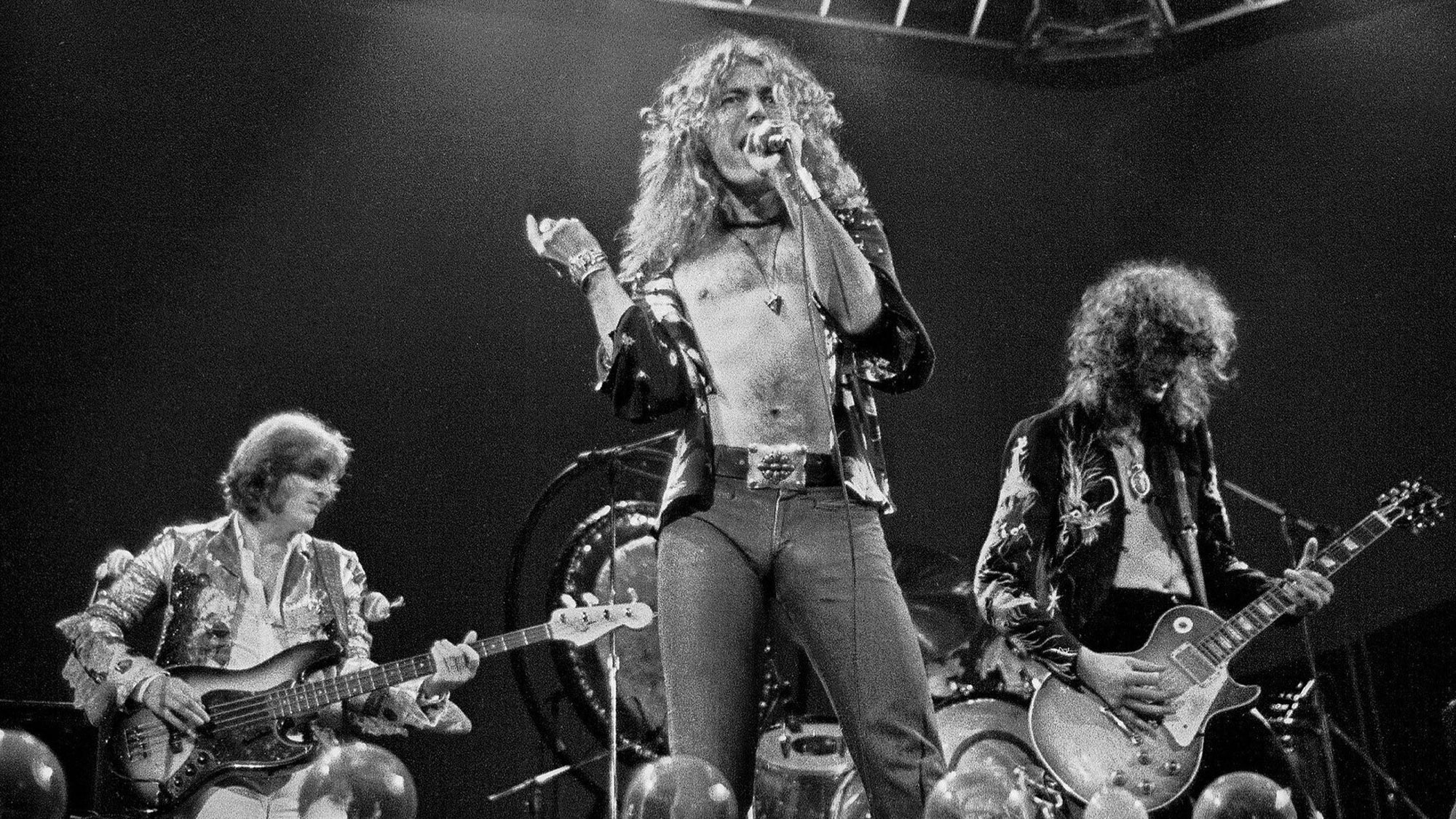 123 ROCK | Led Zeppelin | Robert Plant (Robert Anthony Plant) - August 20, 1948 - West Bromwich, Staffordshire, England, United Kingdom - Lead Vocals, Backing Vocals, Acoustic Guitar, Bass Guitar, Tambourine, Harmonica (1968 - 1980) (1994) (1998), Jimmy Page (James Patrick Page) - January 9, 1944 - Heston, Middlesex, London, England, United Kingdom - Electric Guitars, Rhythm Guitar, Acoustic Guitar, Twelve-string Guitar, Pedal Steel Guitars, Lap Steel Guitar, Slide Guitar, Double Neck Guitar with Six-String and Twelve-String, Bass Guitar, Mandolin, Theremin, Banjo, Dulcimer, The Gizmo, Backing Vocals (1968 - 1980) (1994) (1998), John Paul Jones (John Baldwin) - January 3, 1946 - Sidcup, Kent, London, England, United Kingdom - Bass Guitar, Guitar, Mandolin, Double Bass, Keyboards, Organ, Piano, Acoustic Piano, Electric Piano, Mellotron, Synthesizer, VCS3 Synthesizer, Hohner Clavinet, Hammond Organ, Harpsichord, Moog Synthesizer, Bass Guitar Effects Unit, Recorder, Backing Vocals (1968 - 1980), John Bonham (John Henry Bonham) (Also called : Bonzo, The Beast, Powerhouse) - May 31, 1948 - Redditch, Worcestershire, England, United Kingdom - Drums, Percussions, Timpani, Backing Vocals (1968 - 1980) | Live - Concert - Oakland Stadium - Oakland - California - United States of America - July 23, 1977 | Genre : Hard Rock, Heavy Metal, Blues Rock, Folk Rock, Progressive Rock, Psychedelic Rock | Live | Concert | Photo | 29 | Photograph